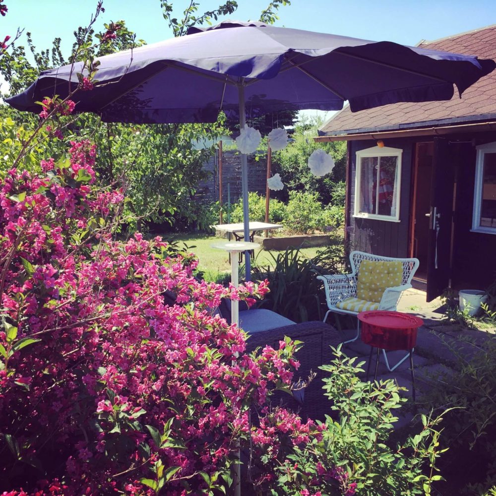 Gartenlaube mit Sonnenschirm und bunten Gartenmöbeln