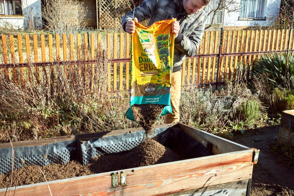 Hochbeet-Erde wird im Beet verteilt